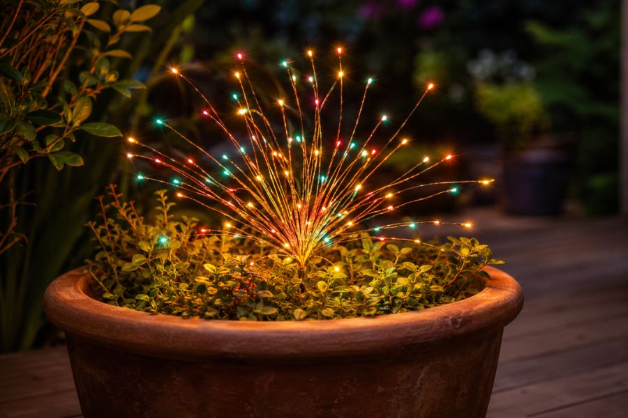 Bendable copper wire solar fairy lights shaped into a starburst in a garden pot